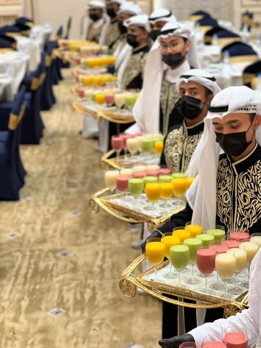 صف فريق الضيافة يحمل صواني المشروبات