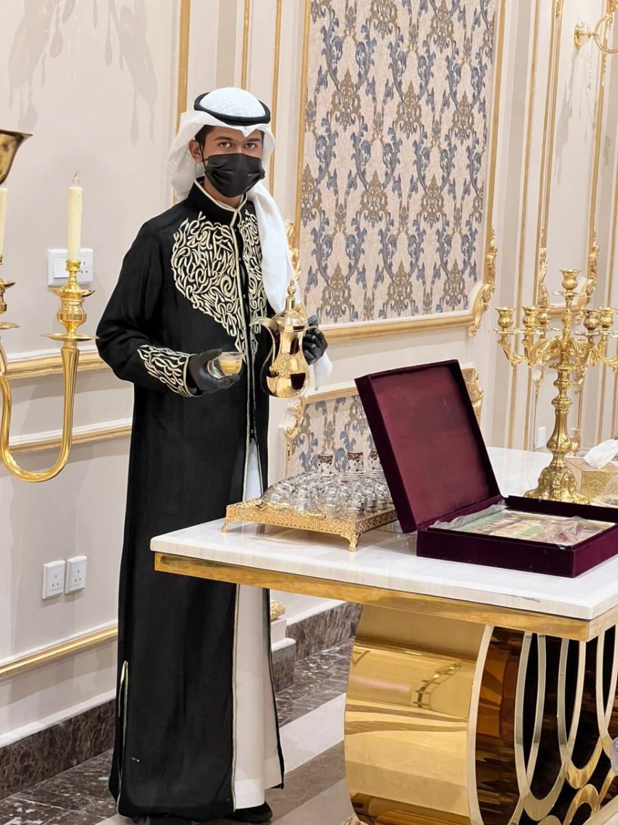 قهوجي يصب القهوة من الدلة بجوار تجهيزات التقديم